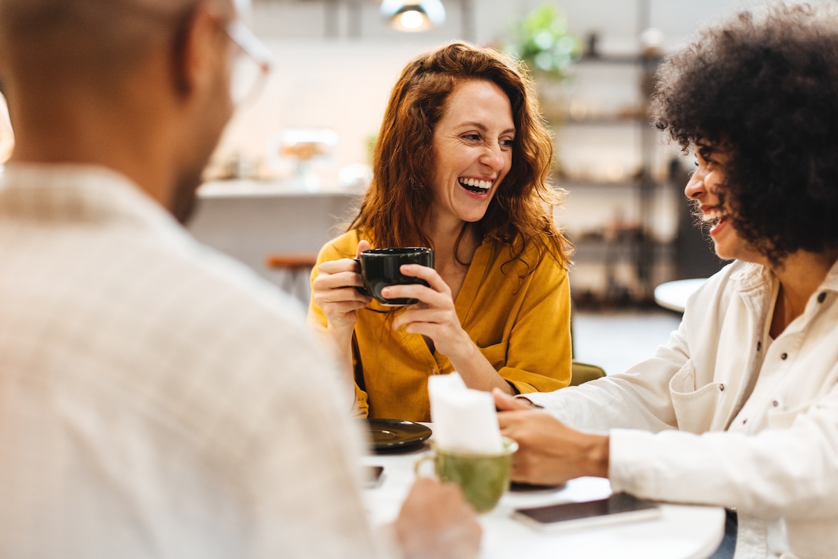 Happy young people catching up with each other over coffee on a friends' date, enjoying the opportunity to spend time together and reconnect. Friends having a relaxed social gathering in a cafe.