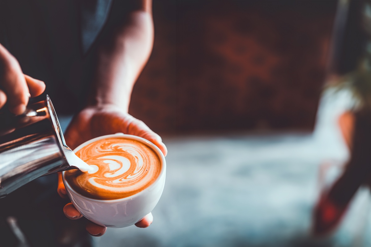 vintage tone of barista pour milk to making latte art coffee at cafe or coffe shop